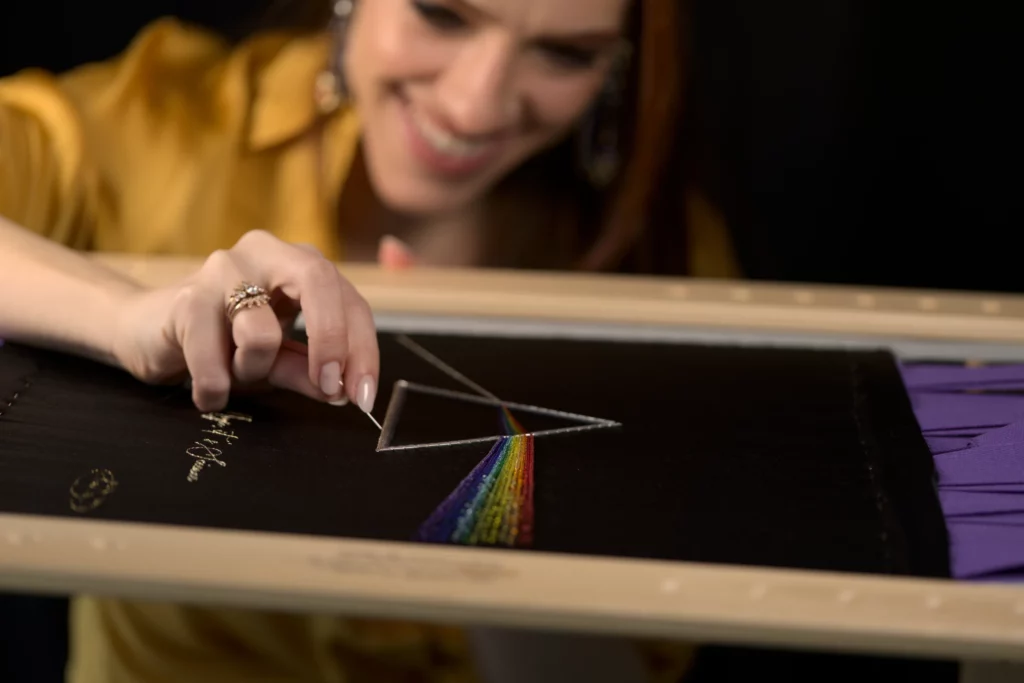 Una obra de arte bordada recibe sus últimos retoques, con delicados ajustes de color que realzan su belleza.