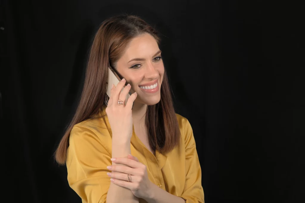 Laura S. Urbina au téléphone, prête à répondre aux demandes de renseignements sur la broderie haute couture et à réserver des ateliers.