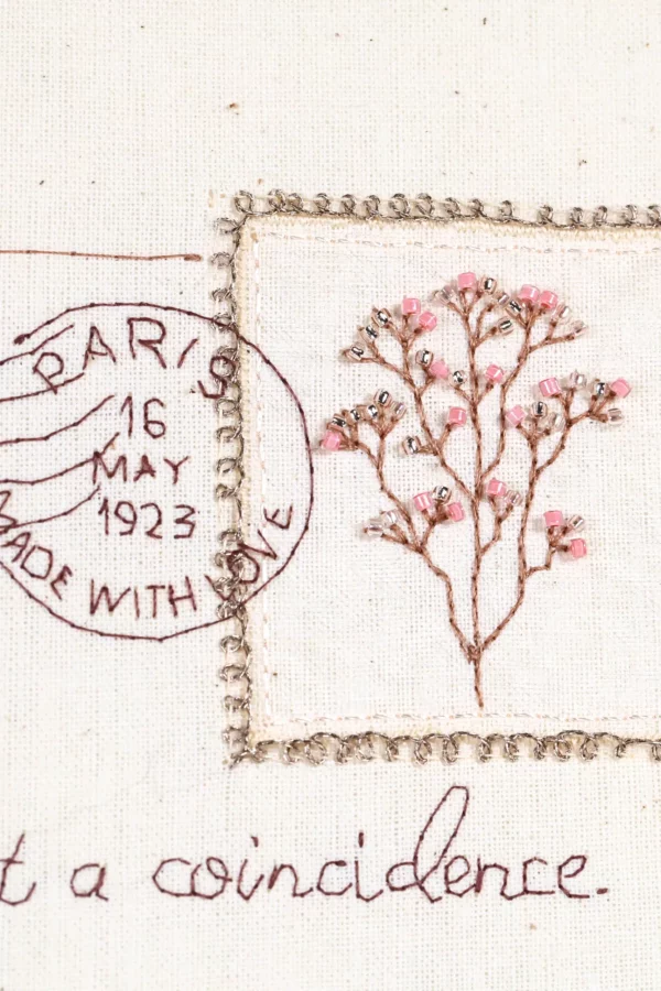 A close-up of the Europa embroidered love letter, highlighting fine details like the stitched Eiffel Tower and vintage postage stamp.
