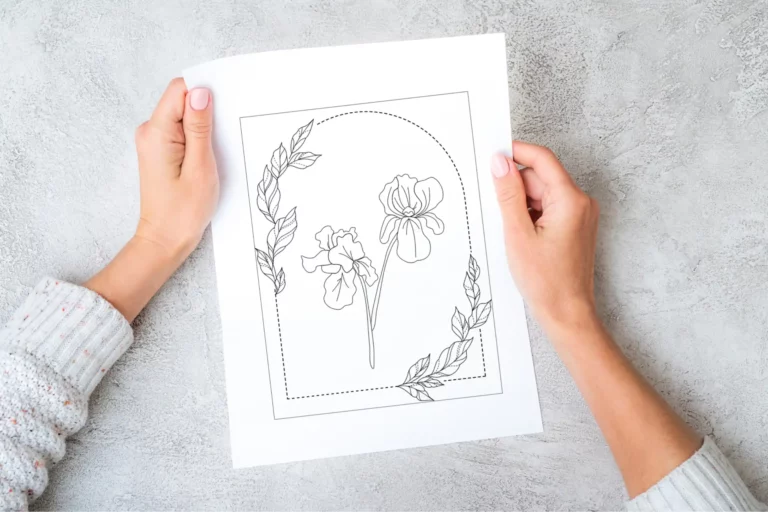 Hands holding a black-and-white technical drawing of a haute couture embroidery design, showcasing precise front and back details.