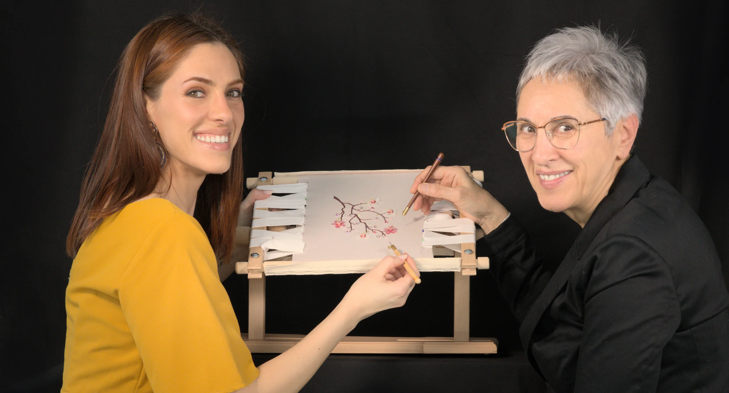Embroidery instructor Laura S. Urbina demonstrating needle and Luneville hook techniques to a student during a hands-on Haute Couture embroidery workshop.