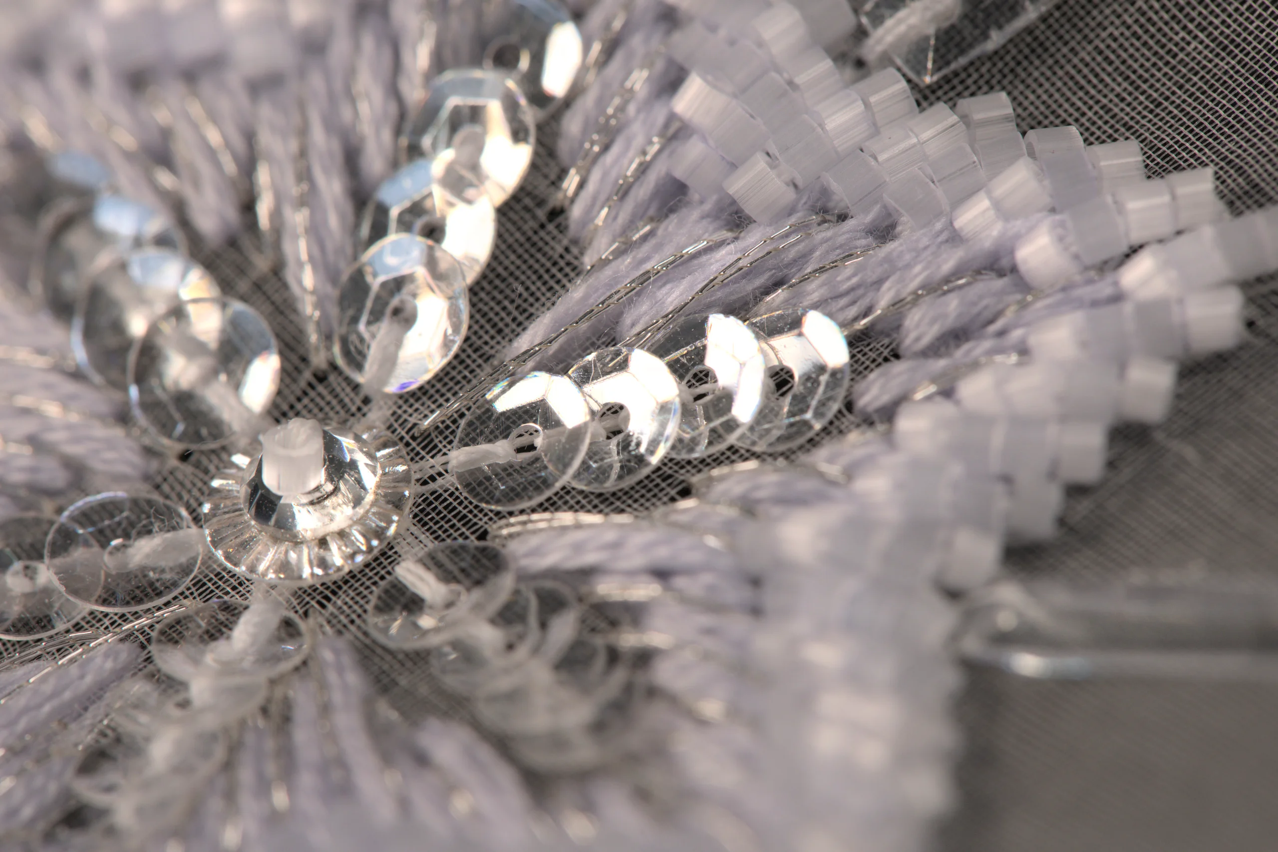 Macro shot of a refined snowflake embroidery pattern, showcasing delicate beadwork and Haute Couture craftsmanship.