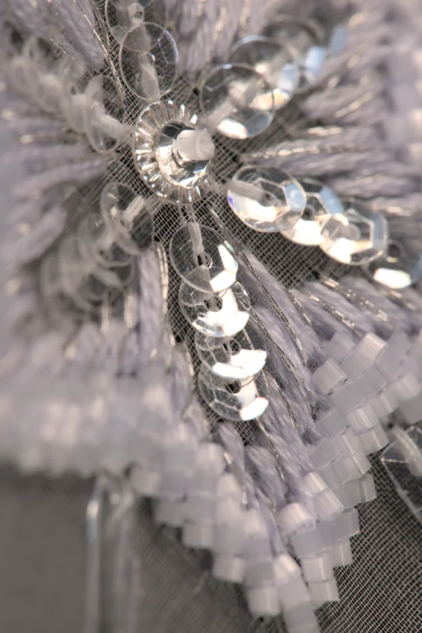 Macro shot of a refined snowflake embroidery pattern, showcasing delicate beadwork and Haute Couture craftsmanship.