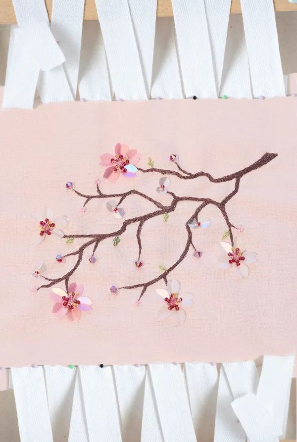 A delicate hand-embroidered cherry blossom branch, Hoshi, adorned with shimmering crystals and sequins, haute couture embroidery design.