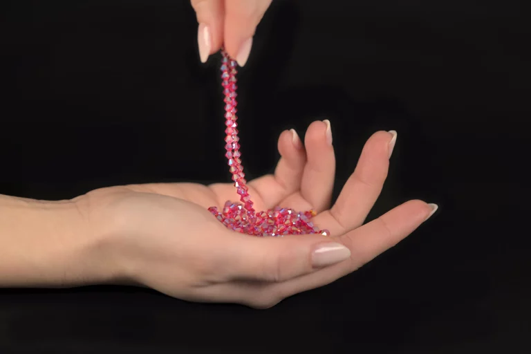 Close-up of Laura S. Urbina’s hands holding luxury Swarovski crystals embroidery supplies, representing excellence in craftsmanship and high-quality textile artistry.