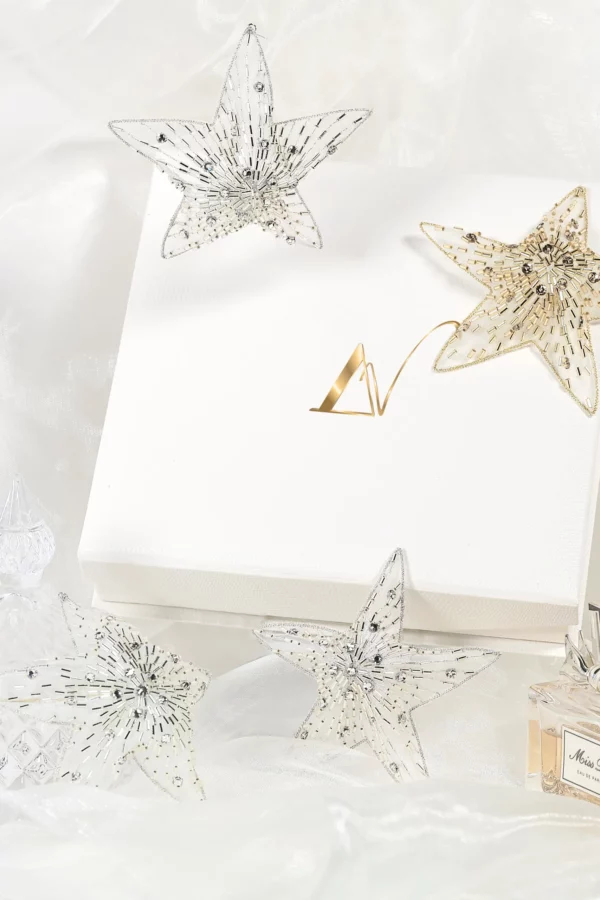 A shimmering hand-embroidered 3D star, Polaris, displayed as a festive Christmas decoration with crystal accents reflecting holiday lights.