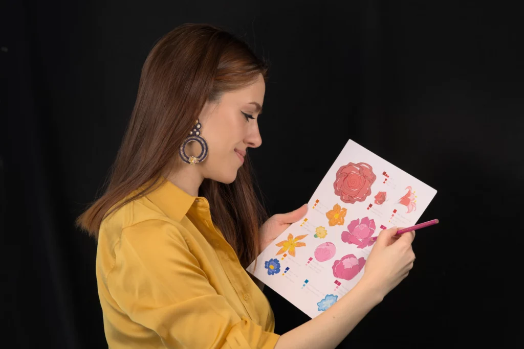Laura S. Urbina dessine au crayon rose un motif de broderie floral imprimé, donnant ainsi vie à un concept de broderie personnalisé.