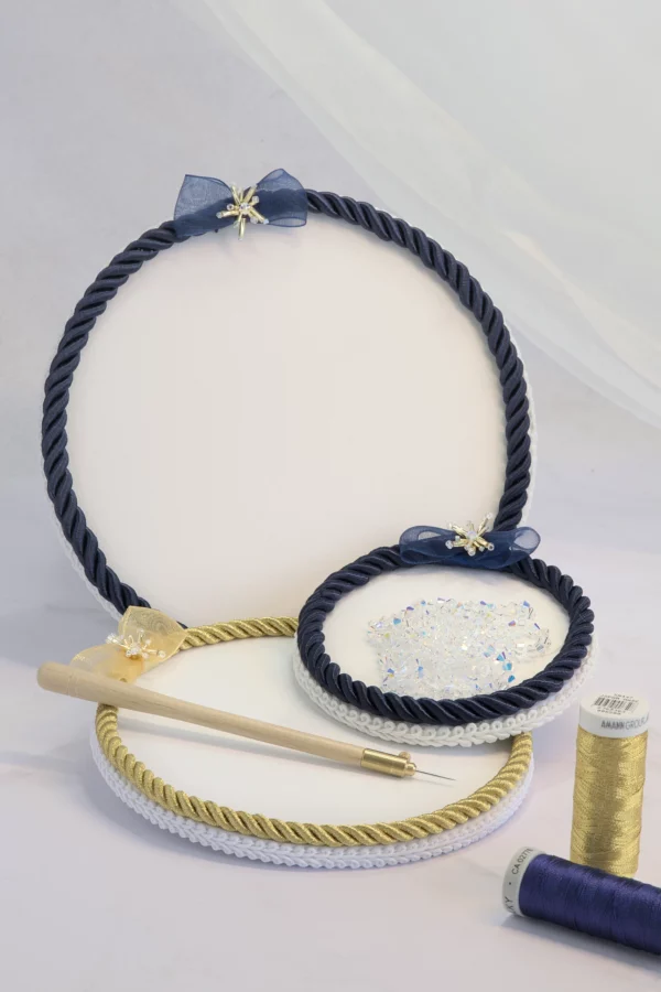 Navy and gold Starlight embroidery beading plates with Lunéville hook, thread bobbins, and beads for couture embroidery.