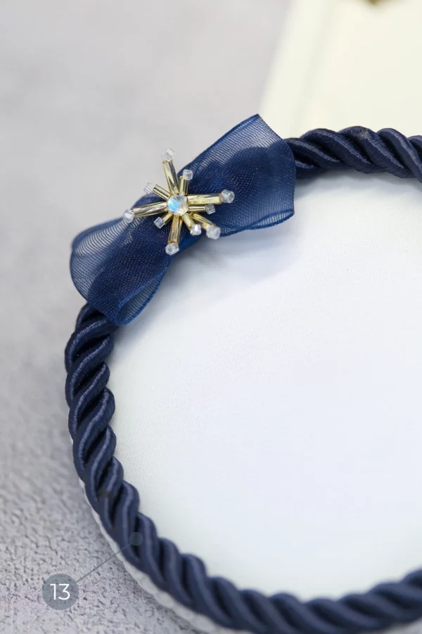 Gros plan sur le pâté de broderie Starlight bleu marin, qui met en valeur les détails brodés en cristal de l'Éclat d’Étoile et le cordon torsadé.