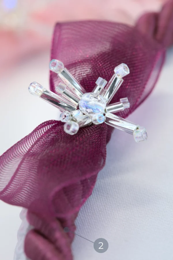 Gros plan sur le pâté de broderie Starlight fuchsia, mettant en valeur le détail Éclat d’Étoile de cristal et le nœud papillon.