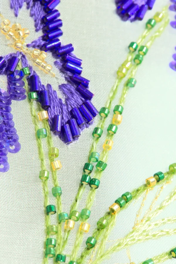 Close-up of Nereid embroidery showing shimmering leaf details stitched with Lunéville hook technique.