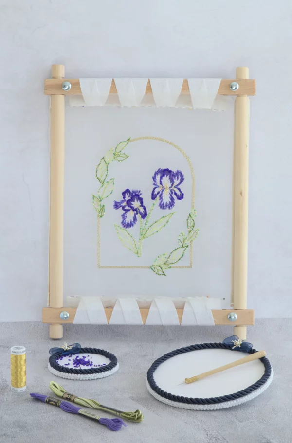 View of Nereid iris embroidery sample framed by leaves, stitched with Lunéville hook technique.