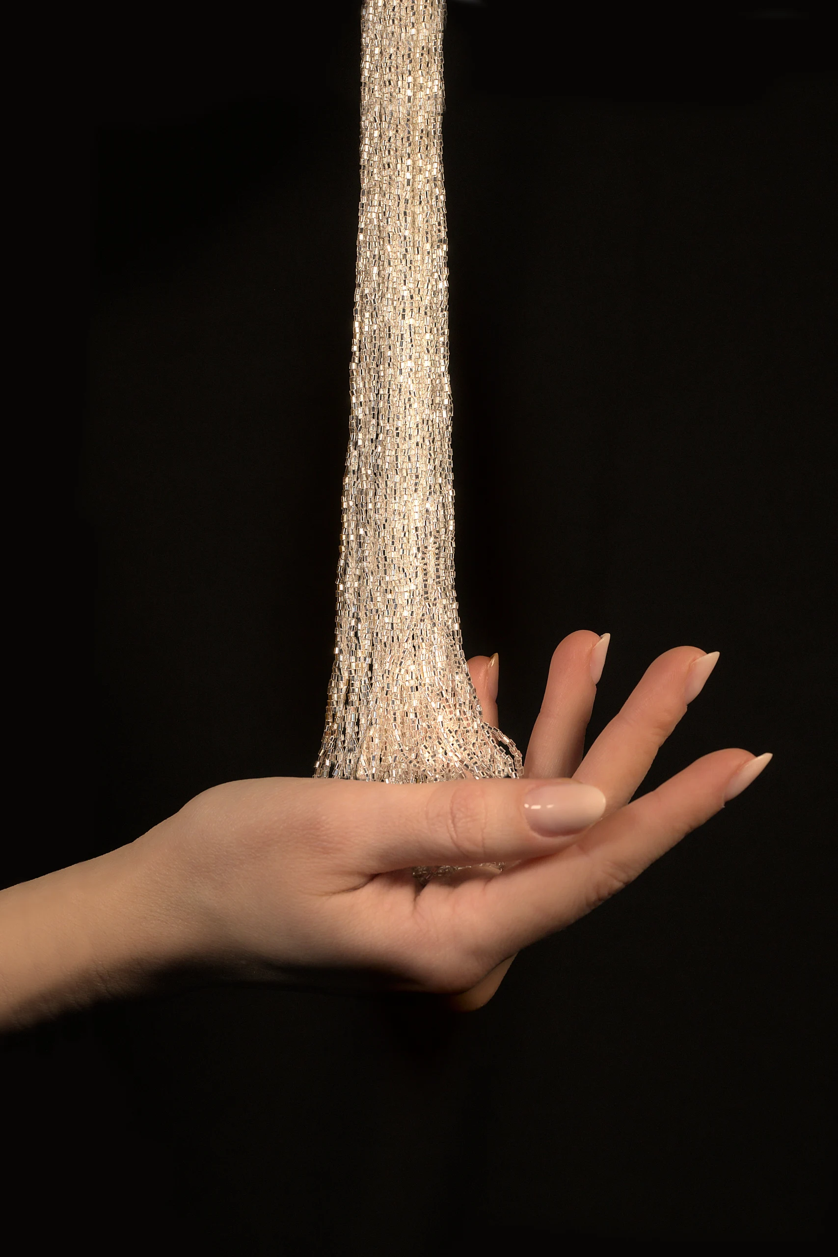 Elegante mano sosteniendo cristales para el bordado de Alta Costura, que muestran una artesanía exclusiva con brillantes abalorios de cristal.