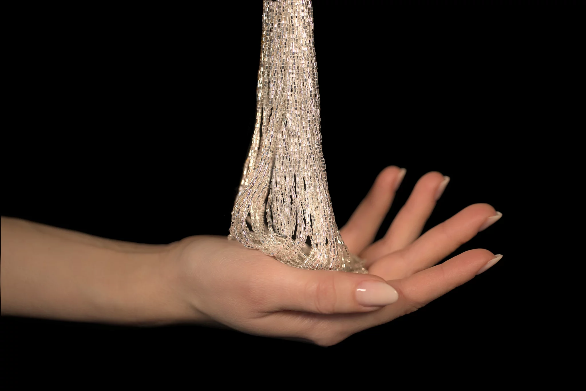 Elegante mano sosteniendo cristales para el bordado de Alta Costura, que muestran una artesanía exclusiva con brillantes abalorios de cristal.