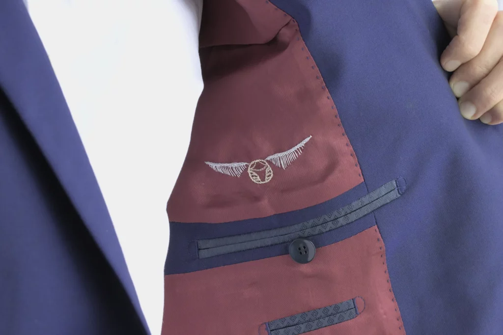 Groom showcasing a wedding suit jacket with custom embroidery of Harry Potter’s golden snitch on the interior lining, adding a unique personal touch.