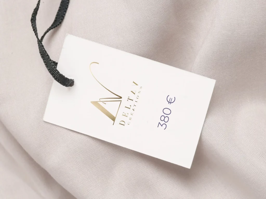 A close-up of a Delta V Créations price tag, showcasing pricing for bespoke embroidery and handcrafted couture pieces.