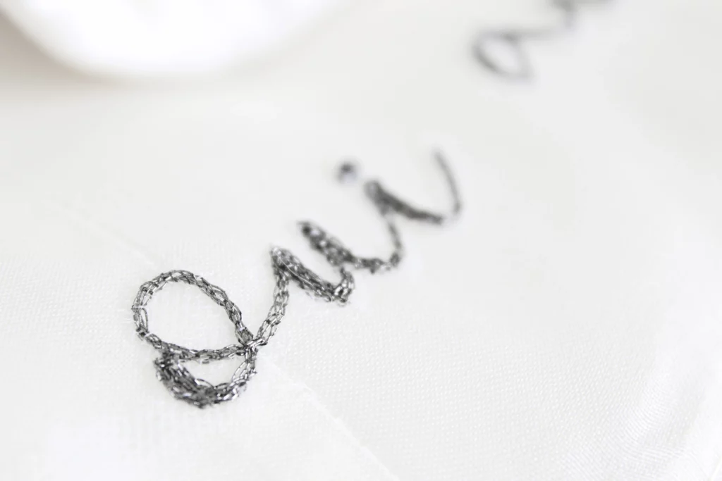 Close-up of oui embroidery on a wedding dress, a delicate custom bridal detail for elegant and personalized wedding gowns.