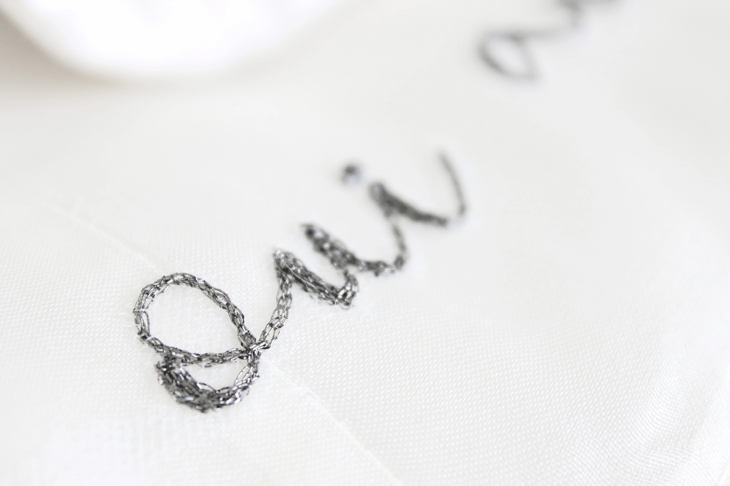 Close-up of oui embroidery on a wedding dress, a delicate custom bridal detail for elegant and personalized wedding gowns.