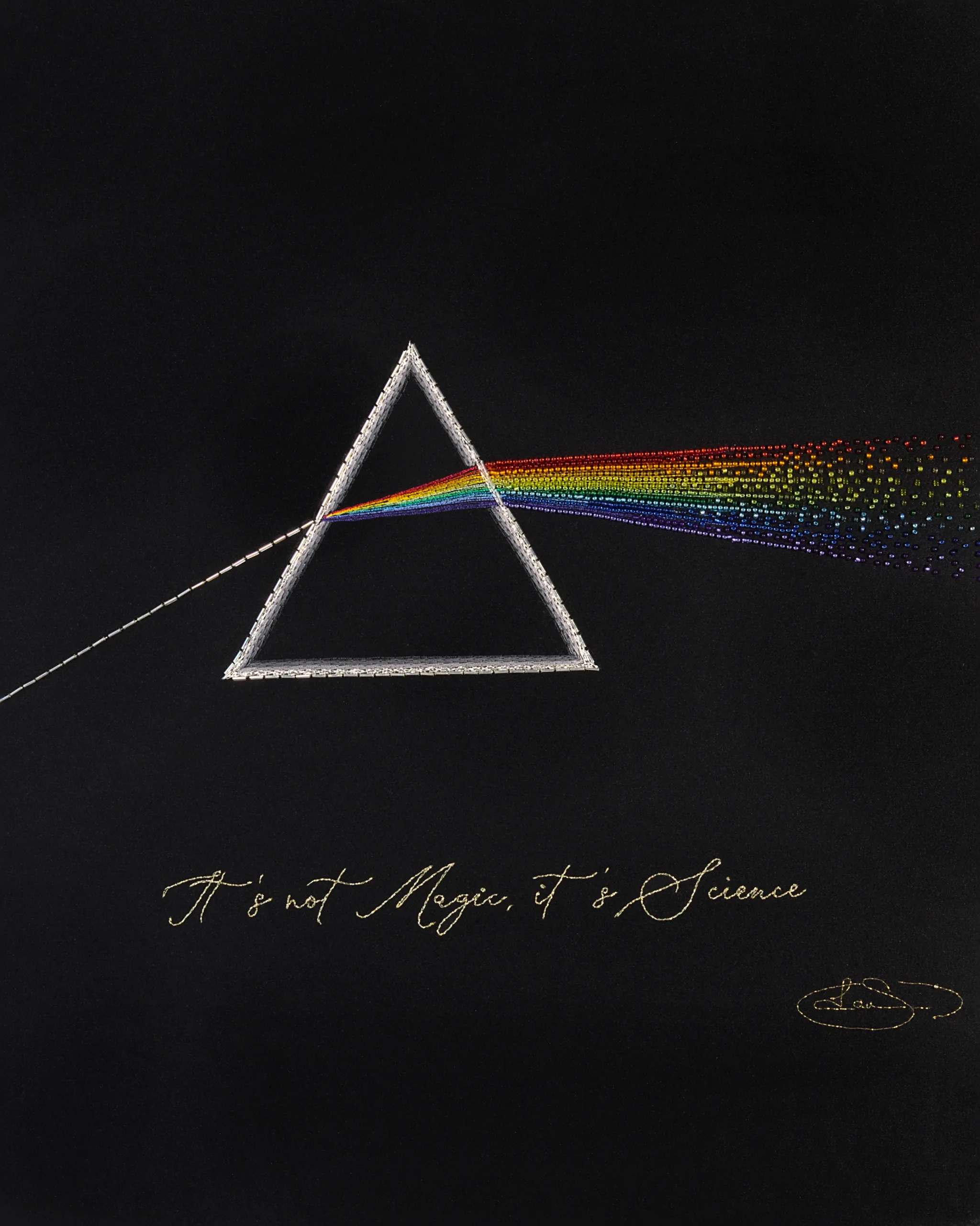 An embroidered prism on black fabric, refracting a white light beam into a colorful rainbow.