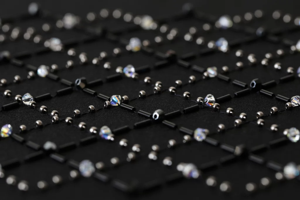 A macro shot of a haute couture embroidery design featuring a geometric grid pattern with black and silver crystals and beads, exuding elegance and sophistication.
