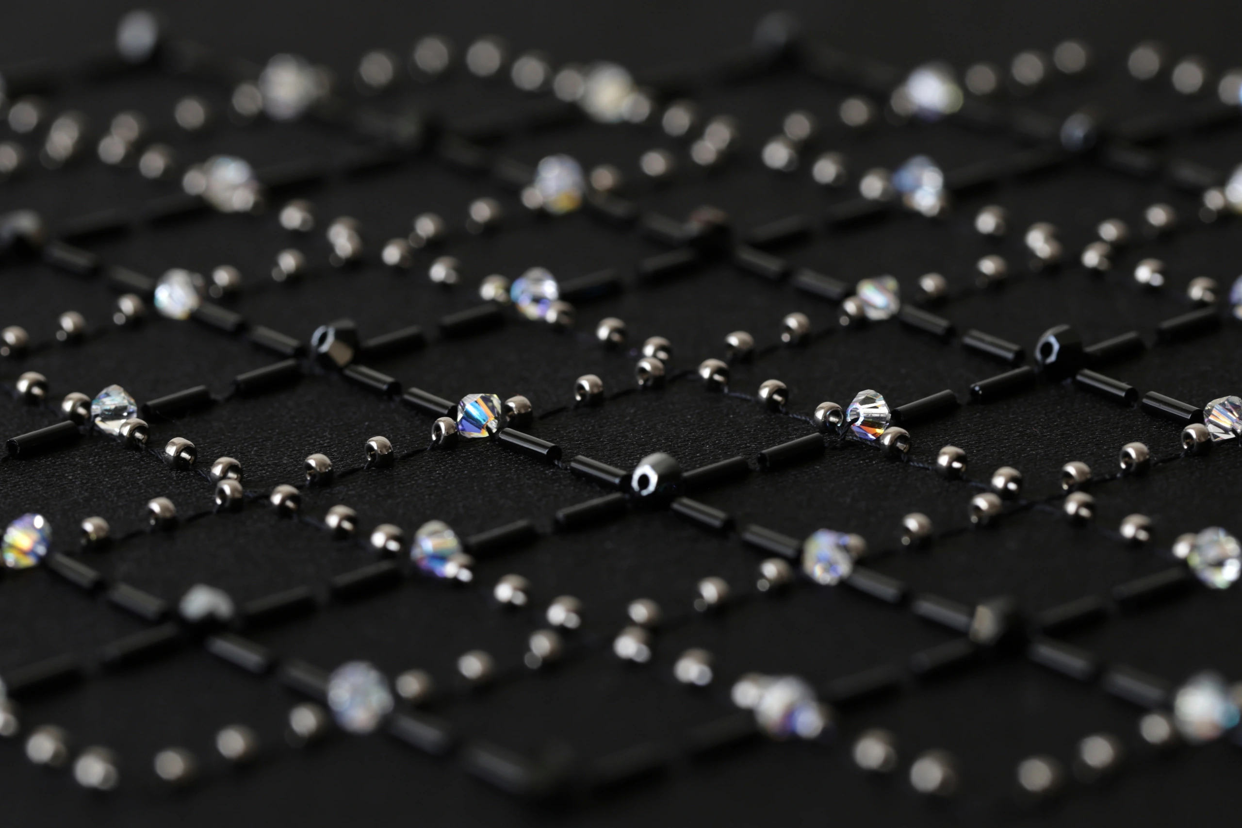 A macro shot of a haute couture embroidery design featuring a geometric grid pattern with black and silver crystals and beads, exuding elegance and sophistication.