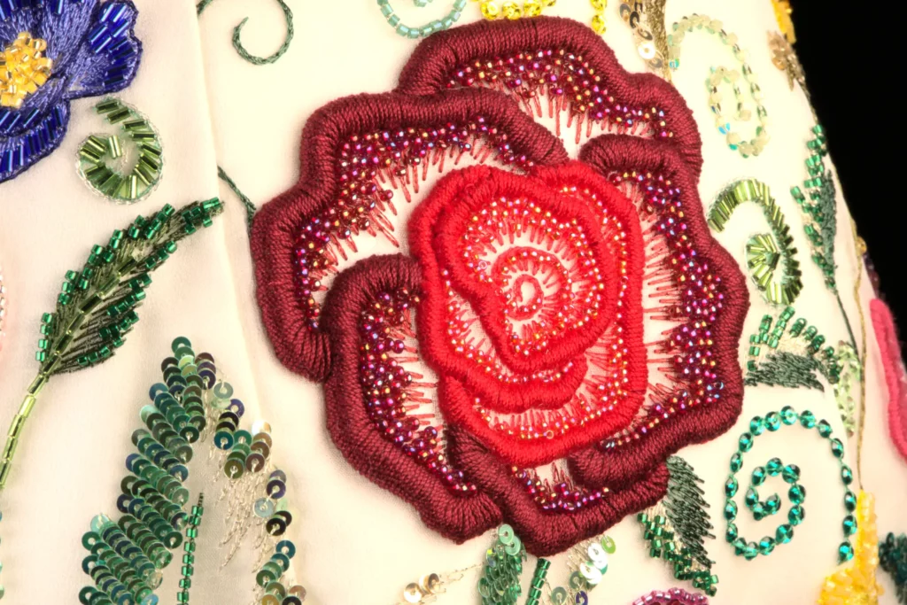 A close-up of a vibrant red embroidered rose, showcasing the fine details and craftsmanship of bespoke haute couture embroidery.