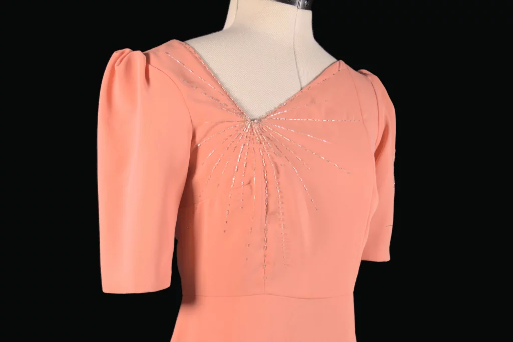 Gros plan sur une robe d'invitée de mariage avec une broderie haute couture sur mesure, caractérisée par une broderie minimaliste mais saisissante en cristaux blancs, réalisée à la main avec précision et élégance.