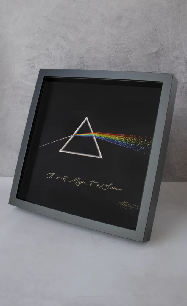 Œuvre d'art d’un prisme brodé à la main illustrant la réfraction de la lumière, mêlant l'art textile à la créativité inspirée par la science.
