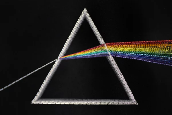 Détail brodé du prisme et du spectre arc-en-ciel avec perles et fils de soie, illustrant la réfraction dans l’œuvre Newton.