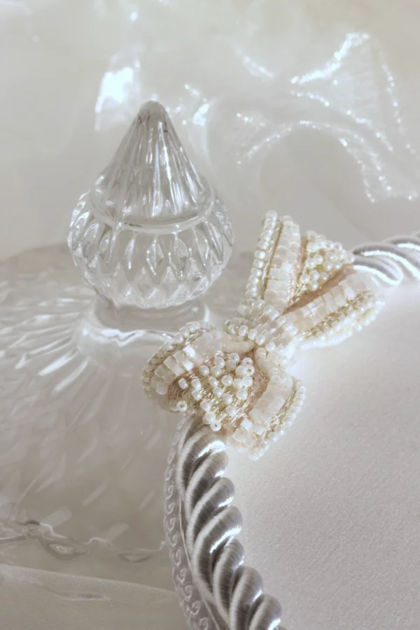 Close-up of the lush embroidered bow in a personalized wedding ring holder for a wedding.