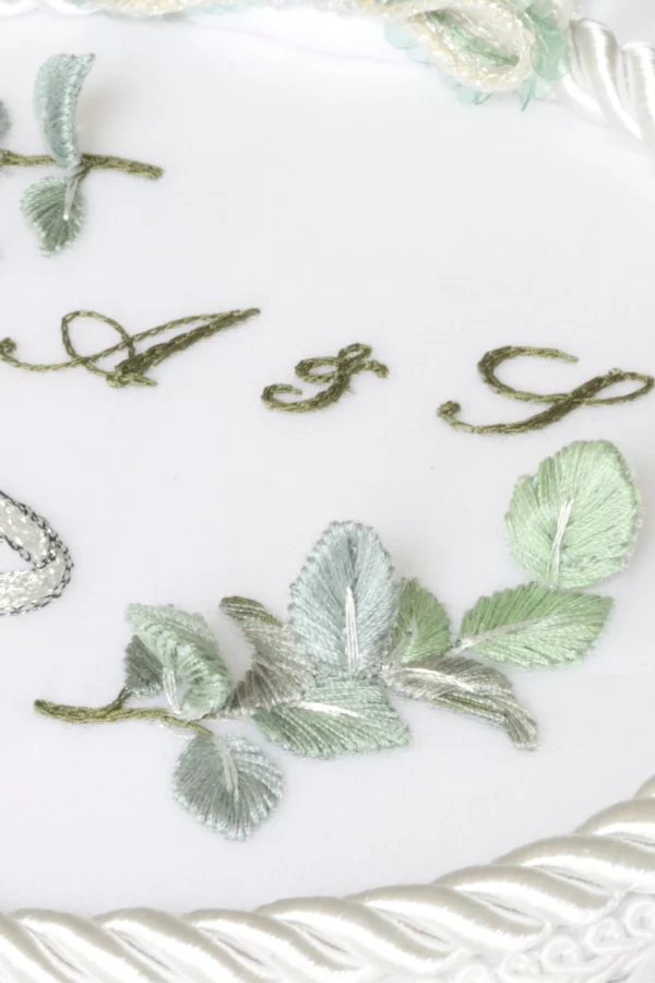 Close up of the embroidery leaves in a personalized wedding ring holder with the couple’s initials.