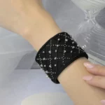 A black embroidered crystal cuff is presented on a model’s wrist, showcasing luxury embroidery and timeless elegance in French prêt-à-porter creations.