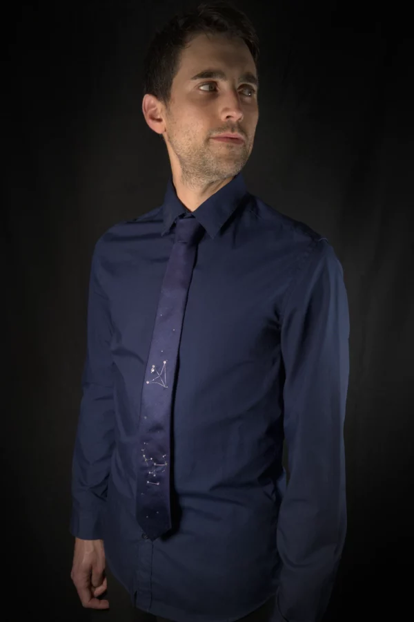 Model wearing navy silk necktie embroidered with Orion and Aquila constellations in silver thread and crystals.