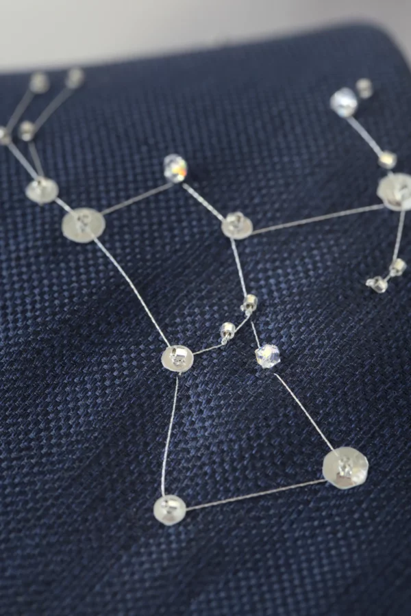 Close-up of Orion constellation embroidery with silver thread and crystals on navy silk necktie.