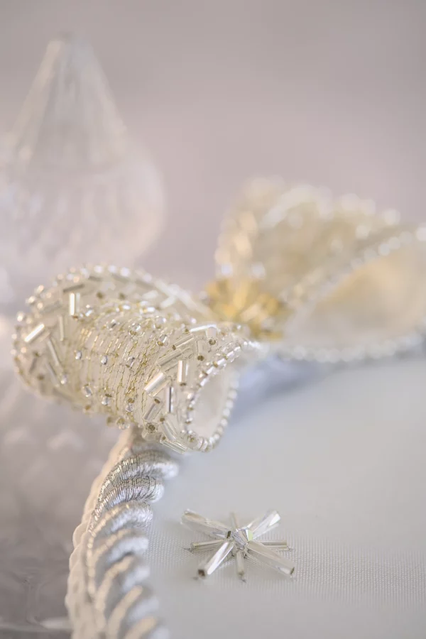 Close-up of the ASTRA wedding ring holder’s embroidered bow with crystal beads and tubes in wheat-ear design, showcasing delicate haute couture embroidery craftsmanship.