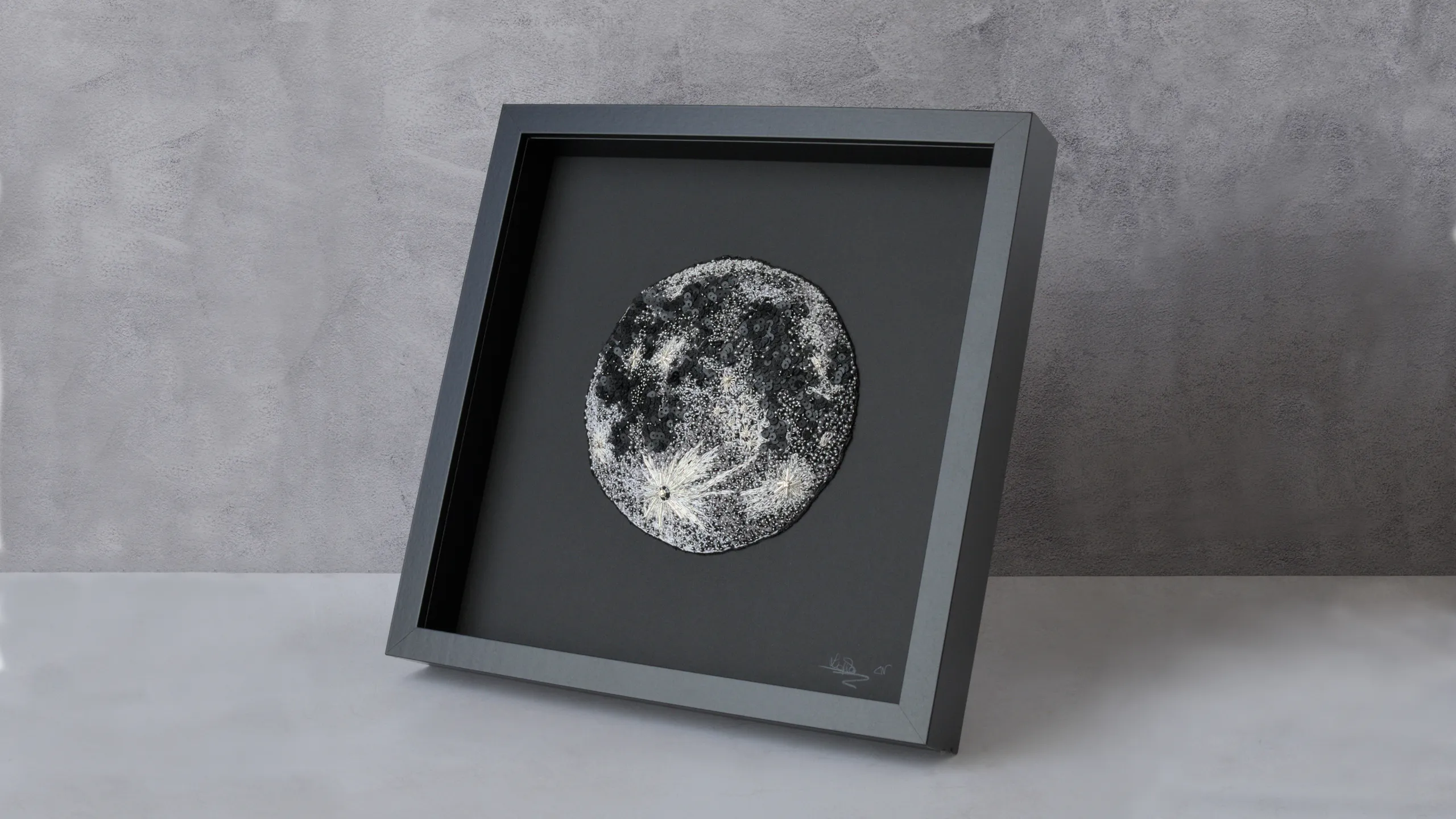 Obra de arte de la luna bordada y enmarcada con abalorios, una pieza de arte textil contemporánea para una decoración de pared moderna.