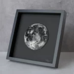 Framed embroidered moon artwork with metallic beadwork, a contemporary textile art piece for modern wall decor.