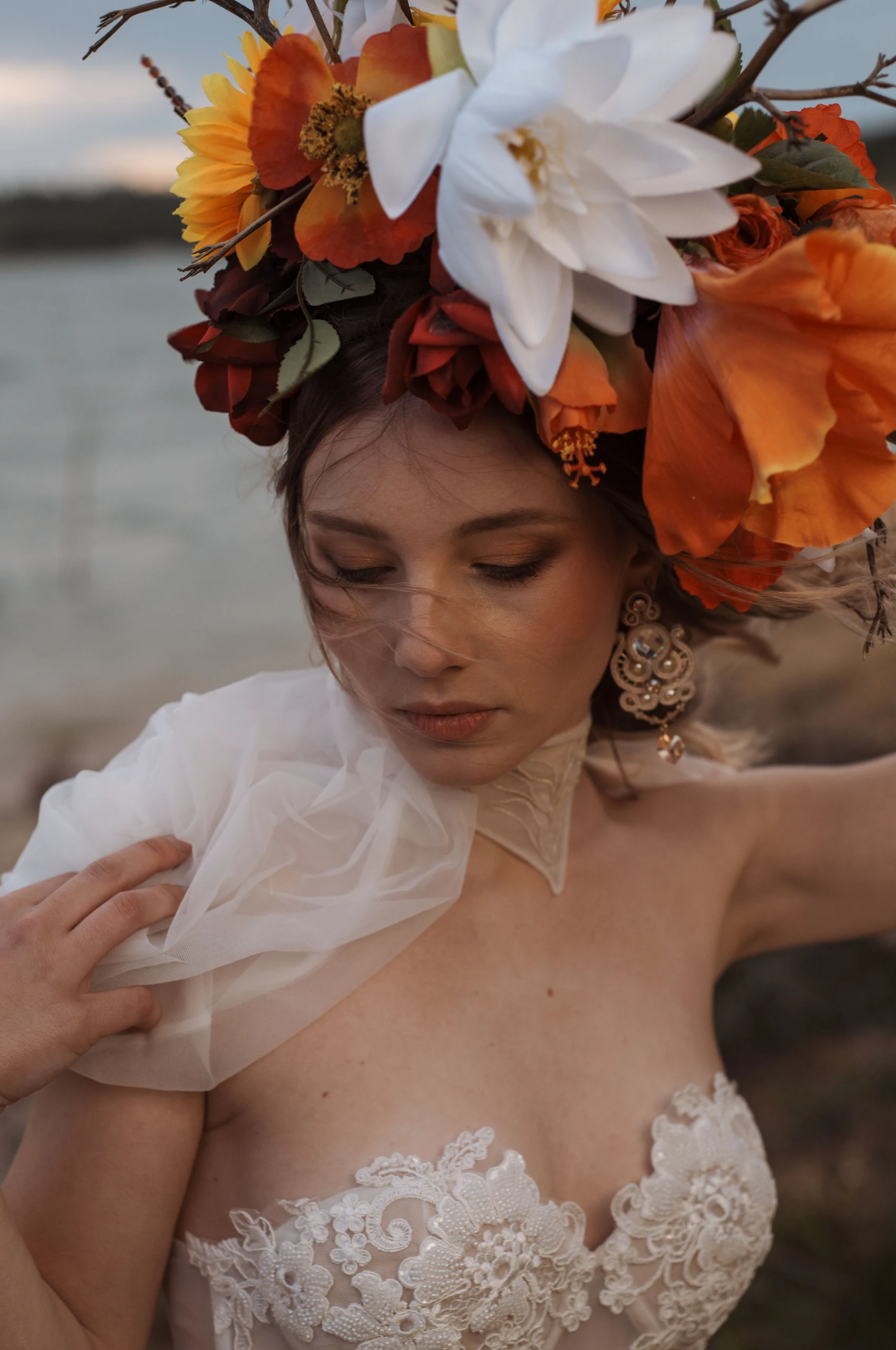 Modelo con bordado nupcial personalizado en el cuello del vestido Hestia, hombros florales y fondo de lago.