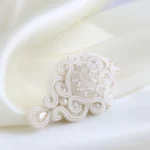 Hand-embroidered bridal hair clip Meissa placed over smooth silk fabric, elegant wedding hair accessory.