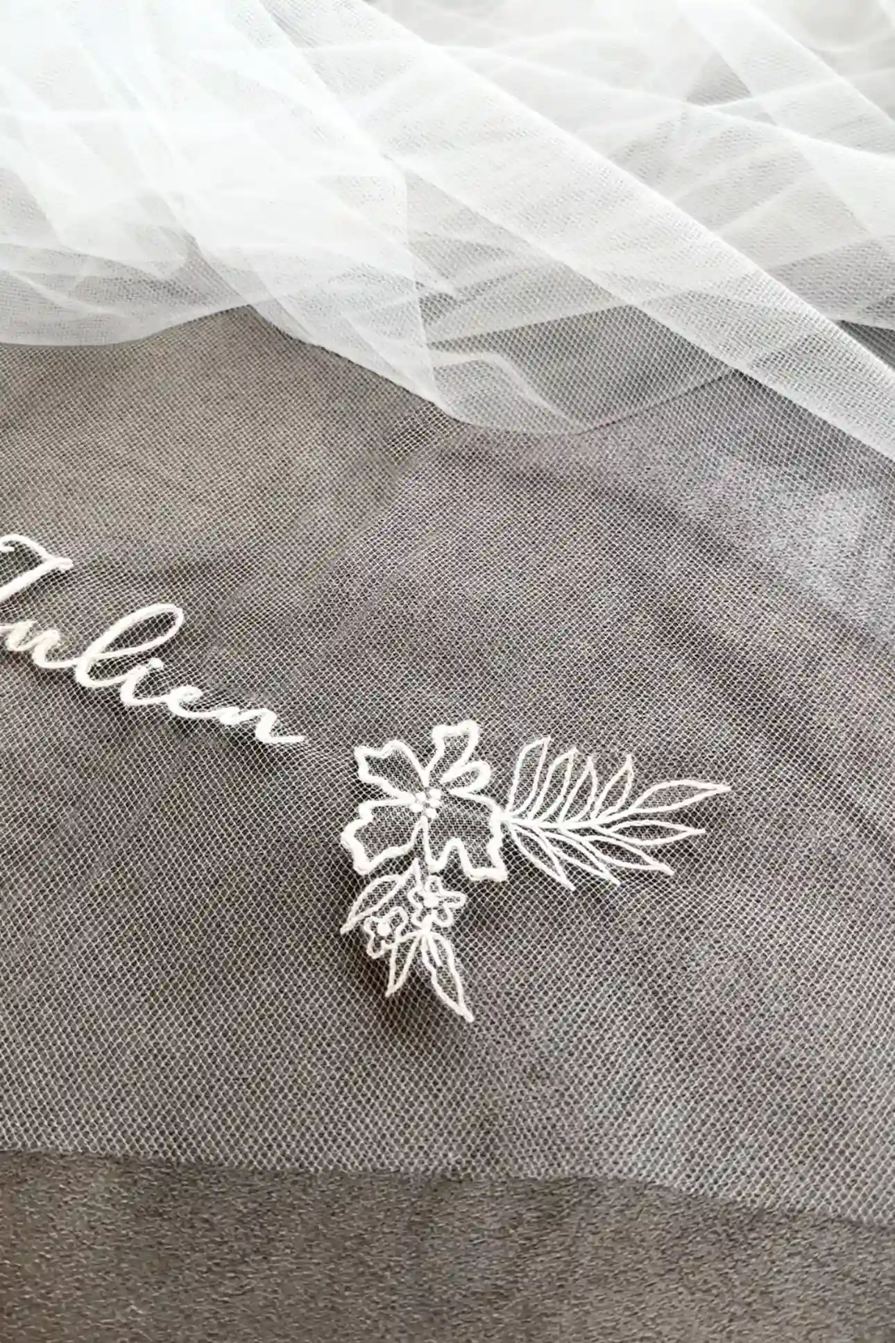 Detalle del velo de novia personalizado con bordado a mano floral y parte del nombre del novio, Julien, hecho en Francia.