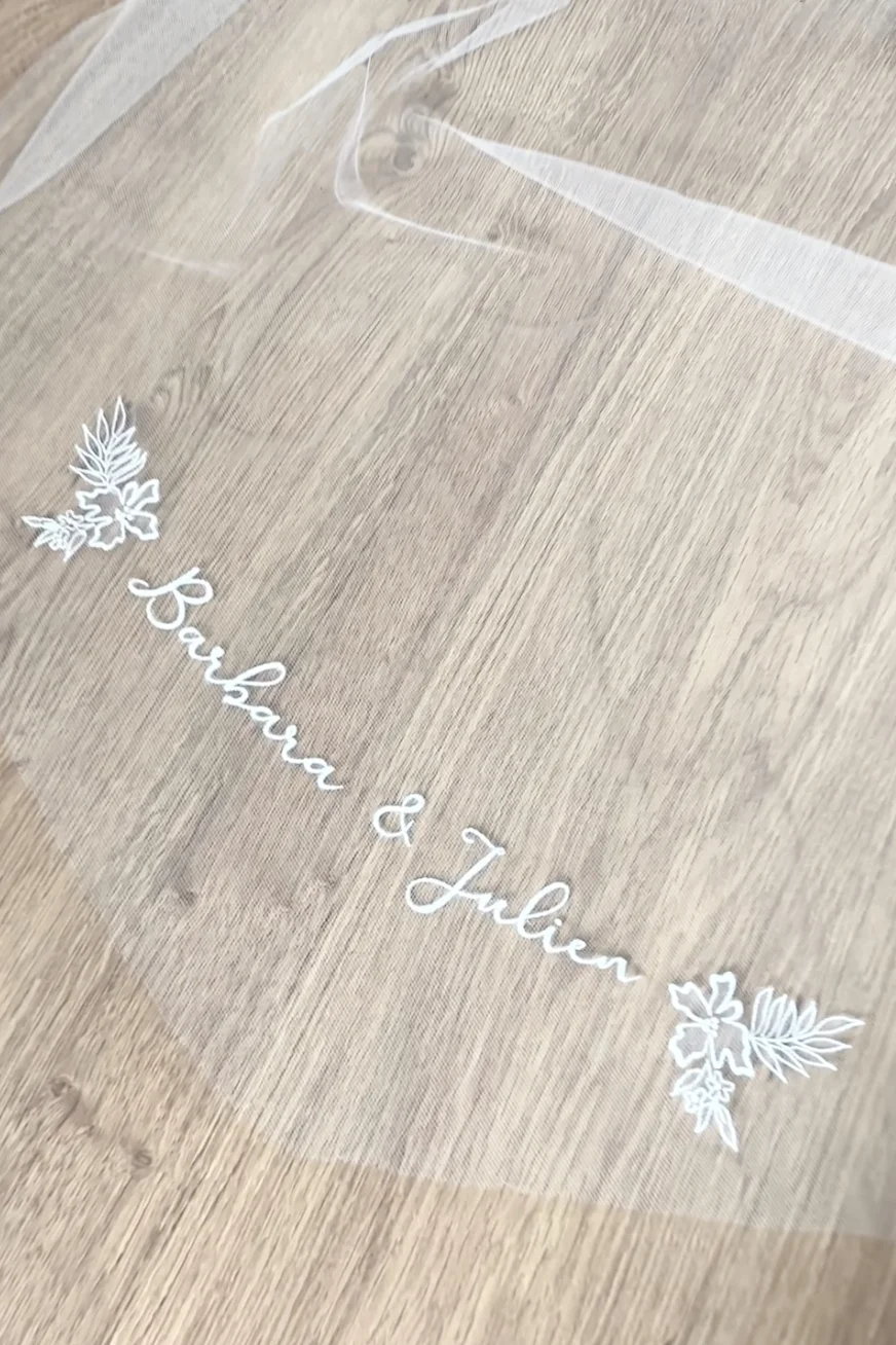 Velo de novia bordado personalizado con bordados de motivos florales que enmarcan los nombres de los novios, realizado sobre tul.