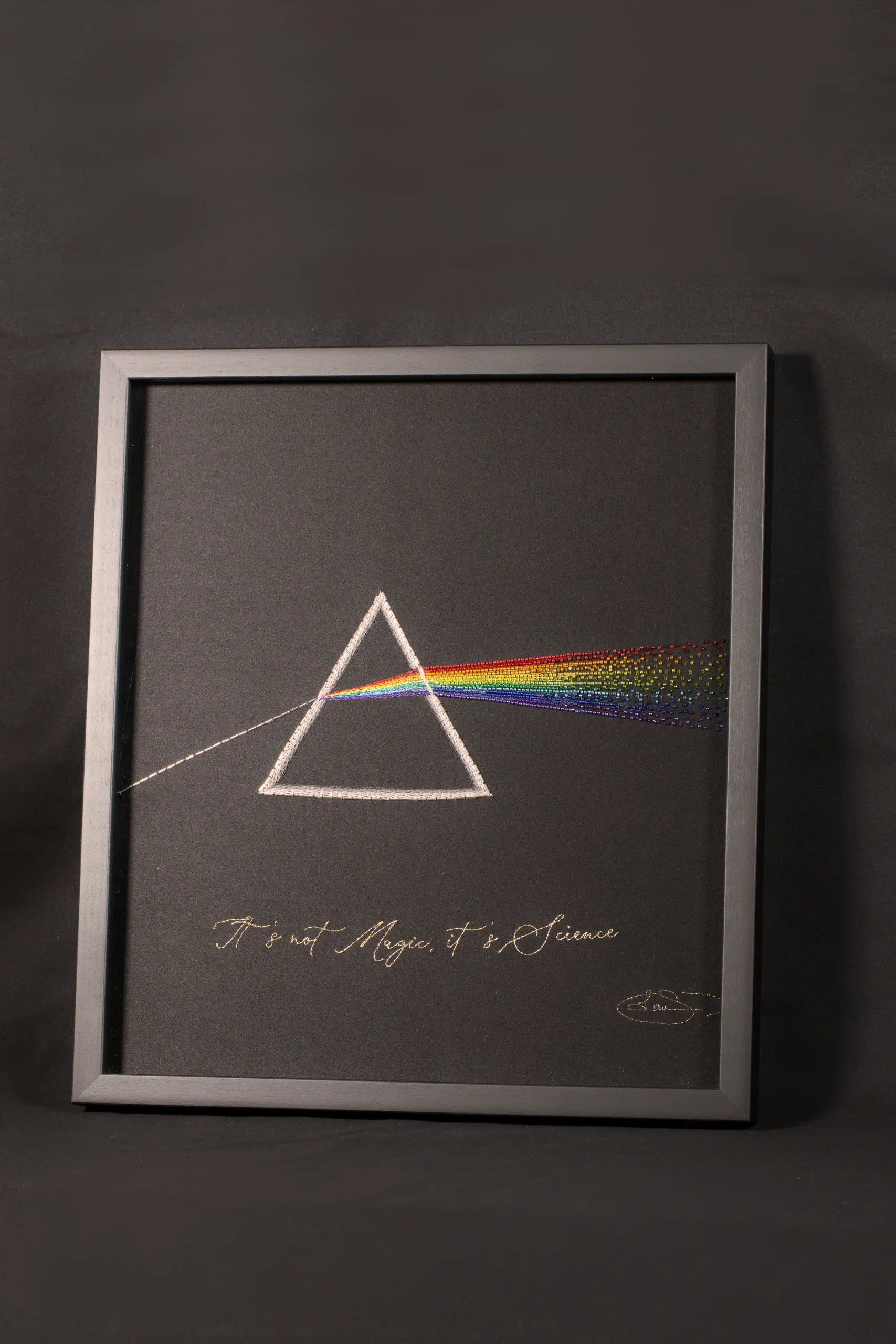 Œuvre d'art d’un prisme brodé à la main illustrant la réfraction de la lumière, mêlant l'art textile à la créativité inspirée par la science.