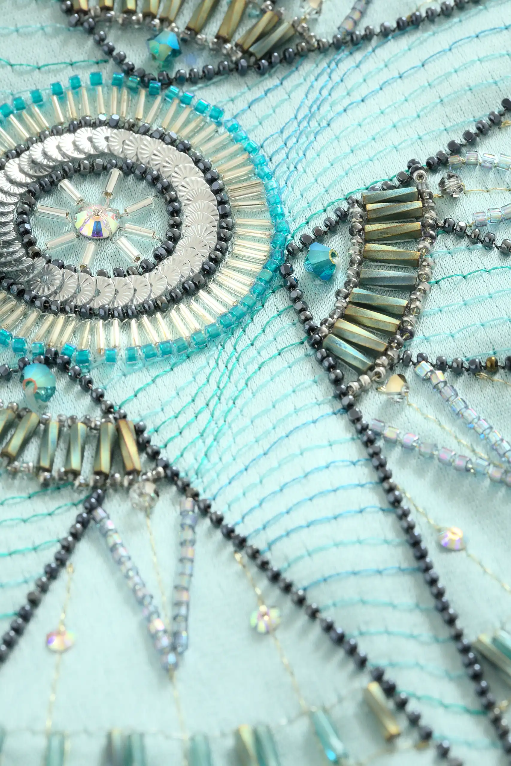 Macro detail of the Alcyone kimono vest’s embroidered compass rose with crystals and fine beadwork.