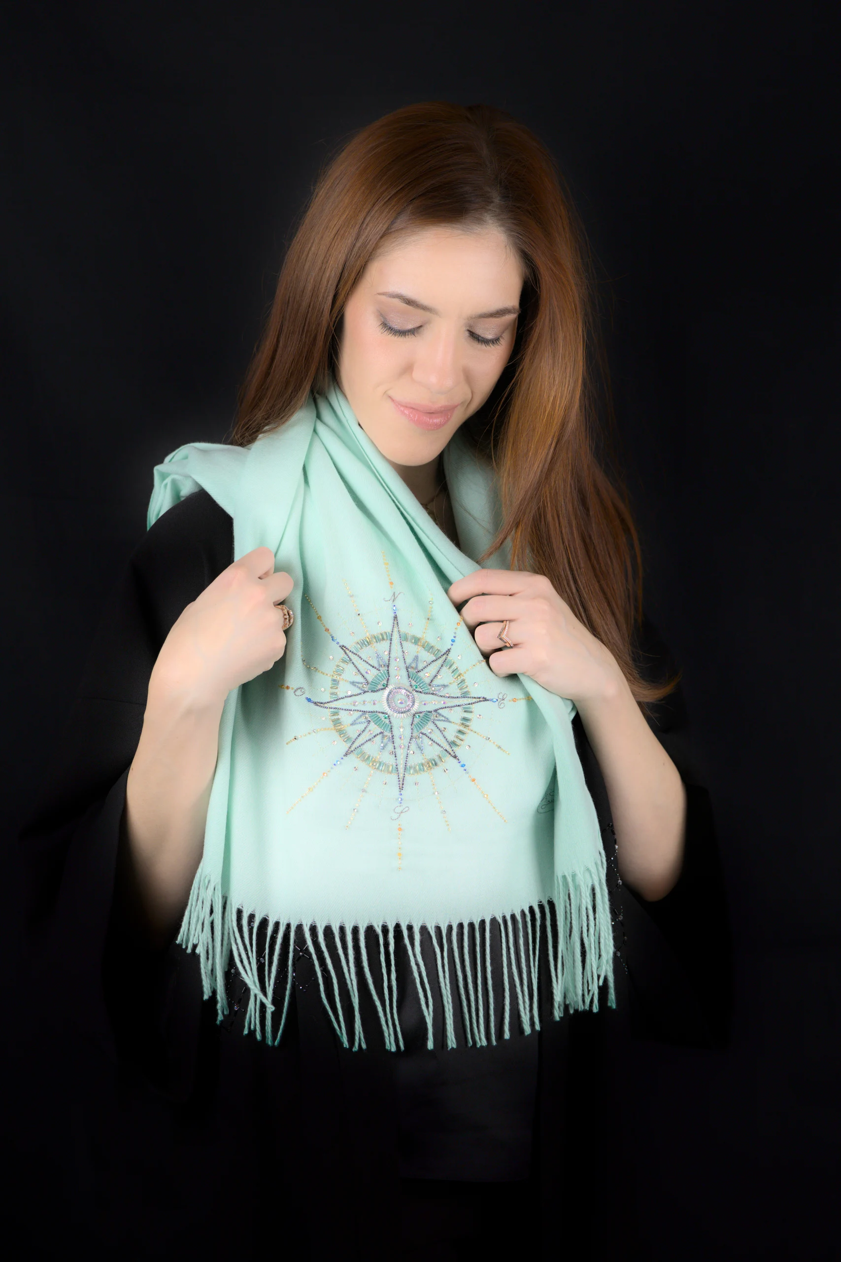 Model wearing the Alcyone turquoise cashmere scarf featuring a hand embroidery.