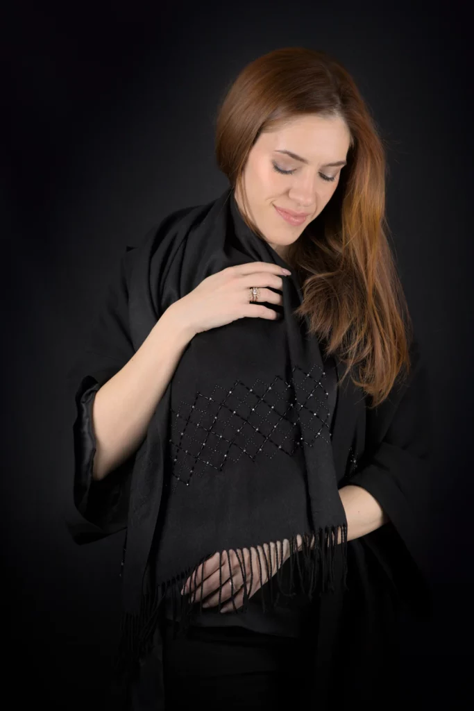Model wearing the Celaeno black cashmere scarf with a subtle hand-embroidered geometric grid.