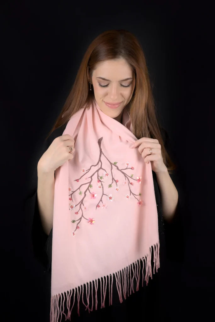 Écharpe en cachemire rose Maia de la collection Pleiades, avec une branche de cerisier brodée à la main, portée par un mannequin.