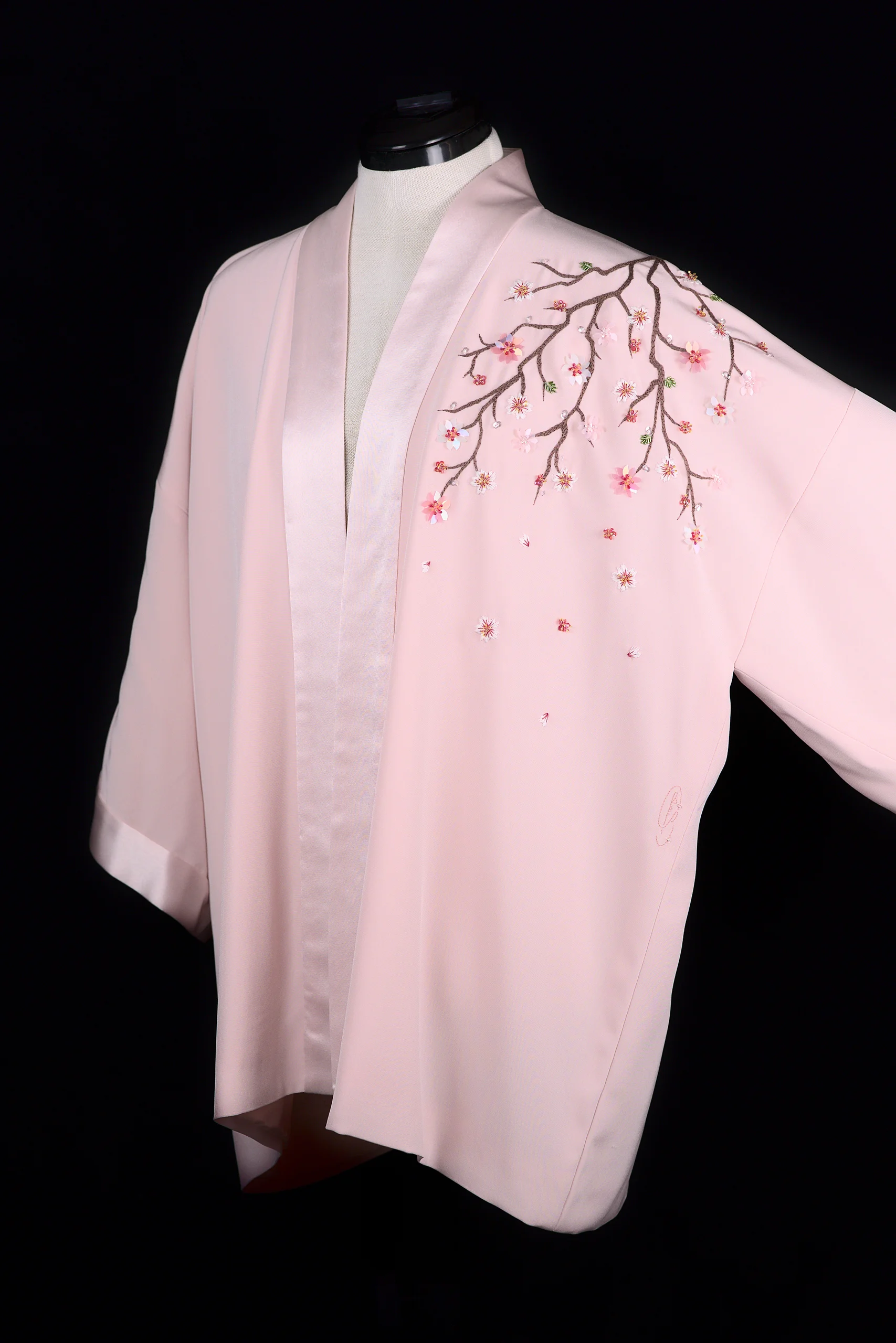 Kimono Maia de la colección Pleiades sobre maniquí, destacando la rama de flores de cerezo bordadas en el hombro.