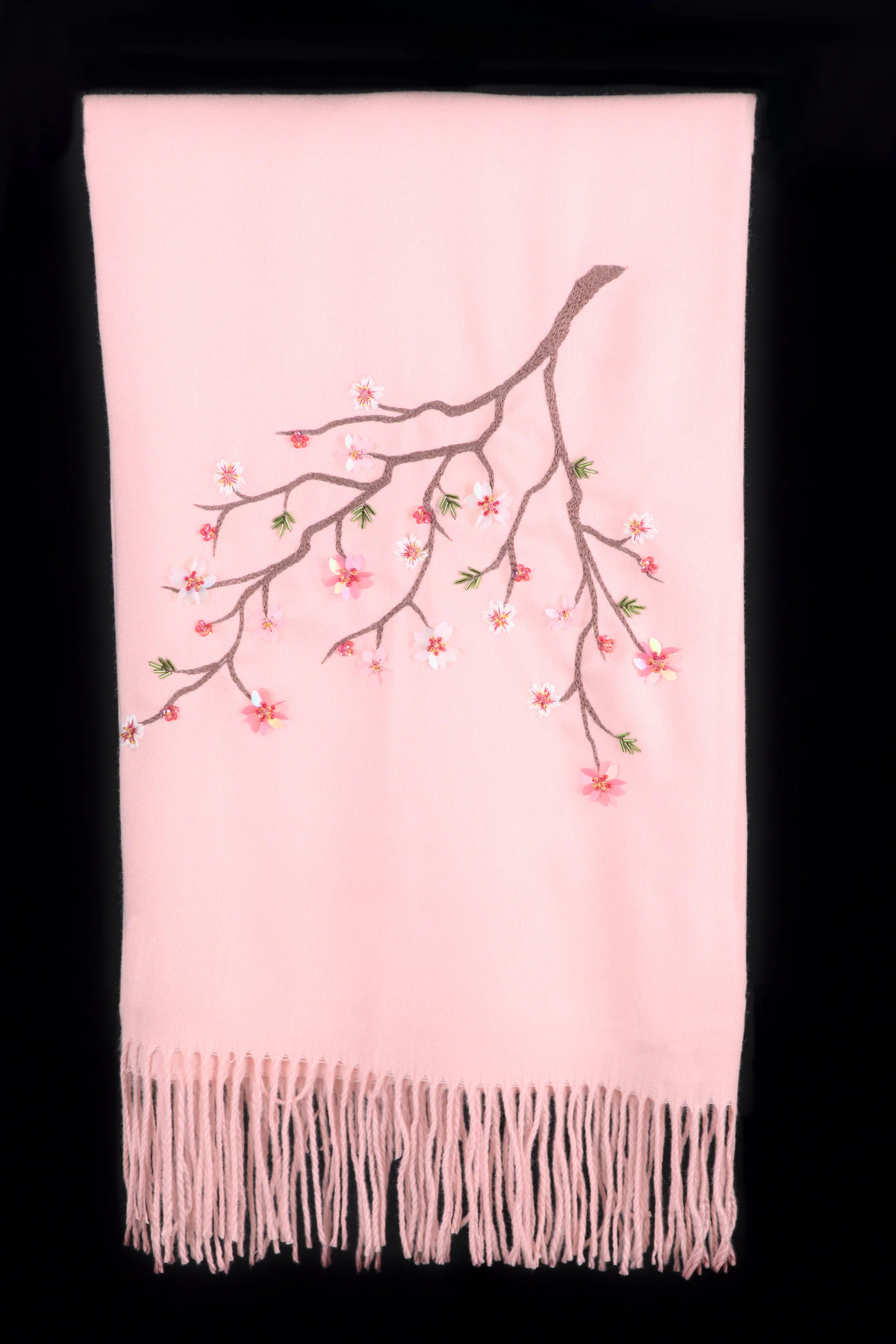 Maia Pleiades cashmere scarf laid flat, showcasing hand-embroidered cherry blossom branch and soft pink fabric.
