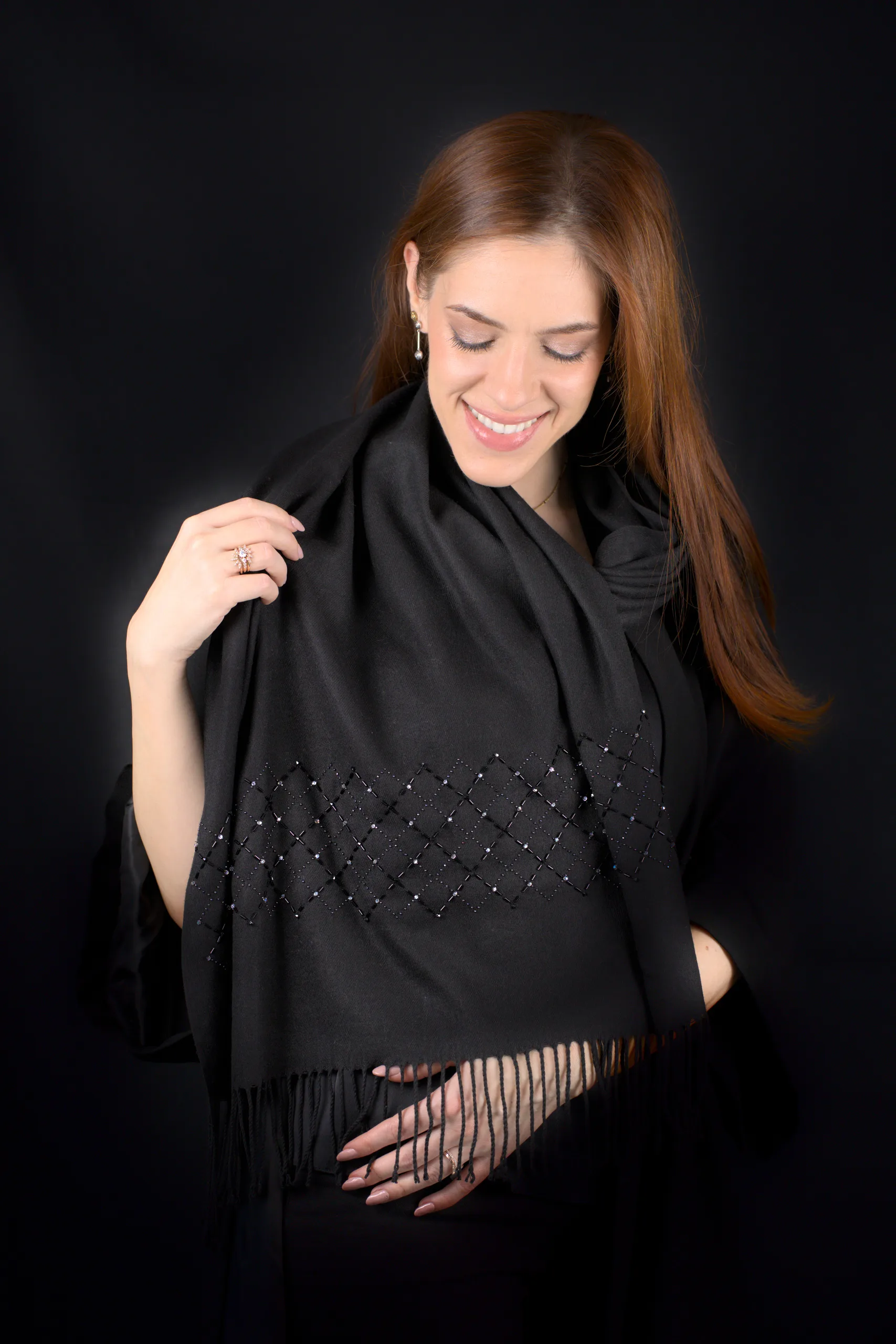 Modelo sonriendo con la bufanda de cachemira negra Celaeno y su cuadrícula bordada a mano.