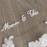 Close-up of the Asteria haute couture bridal veil embroidery featuring the embroidered names Manon & Théo on delicate tulle.